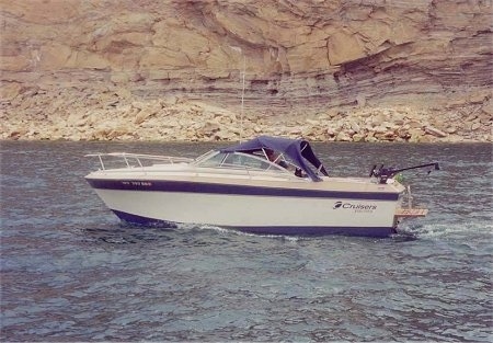 A boat that is in a body of water. There is a little black dog on the boat.