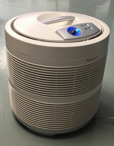 A white HEPA filter sitting on a gray floor against a white wall