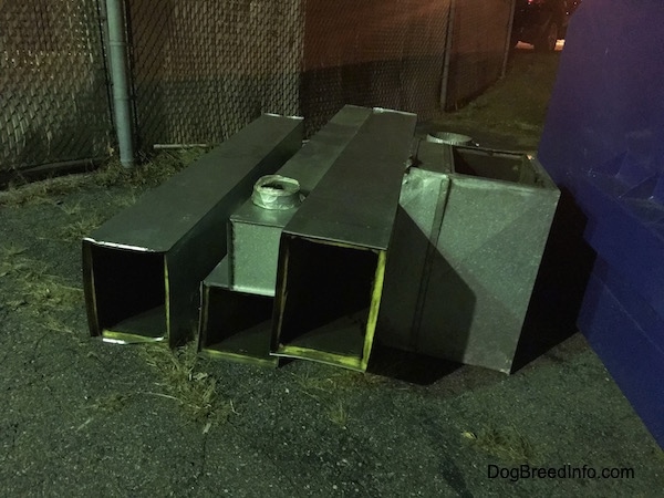 A row of fiberglass lined HVAC air ducts all lined up outside after being removed from a building