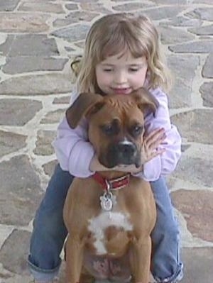 Sara hugging the back of Allie the Boxer on the stone porch