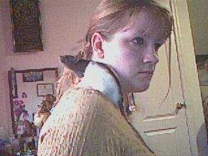 A black and white Fancy Rat is standing on a persons shoulder. The Rat is looking up and to the left.