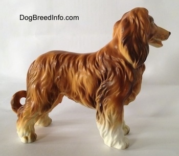 The right side of a brown with white Vintage porcelain Lefton Japan Afghan Hound dog figurine with a lot of texture for the long coat. It is holding its tail down low.
