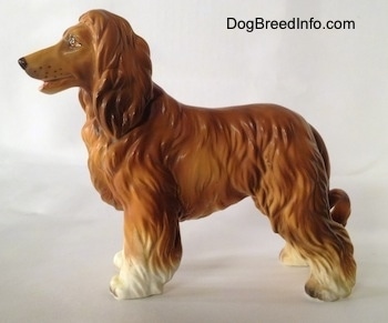 The left side of a brown with black and white Vintage porcelain Lefton Japan Afghan Hound dog figurine. The dog has a long snout with painted dots on it to be the wiskers.