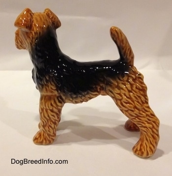 The left side of a shiny black and brown Vintage Airedale Terrier dog West Germany Goebel figurine with its tail up high over its back.