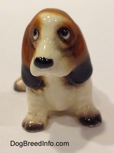 A black, brown and white ceramic Basset Hound figurine. The figurine shaping is not precise.