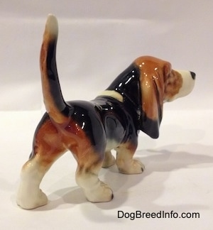 The back right side of a black with white and brown Basset Hound figurine. The figurine has great painting details.