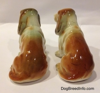 The back of two brown and white with black ceramic Basset Hound figurines. The figurines are very glossy.