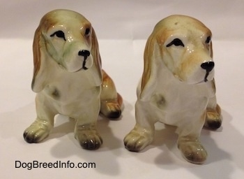 Two brown and white with black ceramic Basset Hound figurines. The figurines black circle eye details.