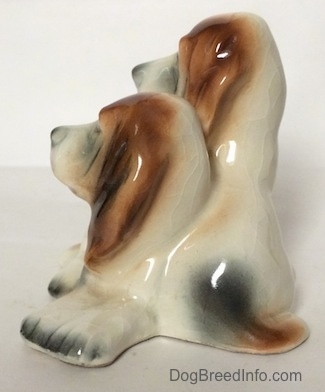 The left side of a ceramic Basset Hound figurine that is two Basset Hounds. The paws on a figurine are lacking detail.