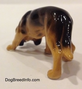 The back left side of a brown and black Hagen Renaker Miniature Bloodhound figurine. The tail of the figurine is very easily distinguishable from the rest of the body.