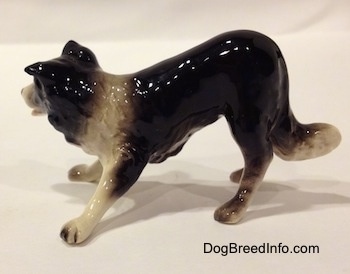 The left side of a Hagen-Renaker miniature black with white Border Collie figurine. The figurine is glossy.