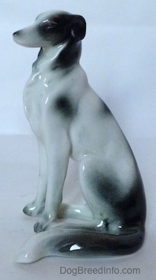 The left side of a white with black vintage Borzoi figurine. The figurine has black circles for eyes.