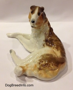 The back side of a brown, white and tan Vintage porcelain Lomonosov Borzoi figurine. The eyes of the figurine are black circles.