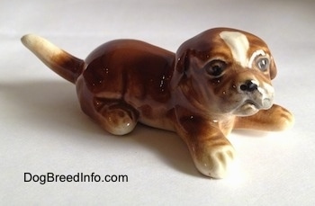 The front right side of a brown with white Boxer puppy figurine. The figurine is very detailed.