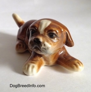 A brown with white Boxer puppy figurine. The figurine has lightly detailed paws.