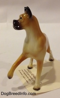 A tan with black and white Boxer mama figurine. The figurine has black circles for eyes.