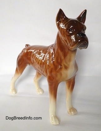 The front right side of a brown with black and white Boxer dog figurine. The eyes of the figurine are hard to differentiate from the face.