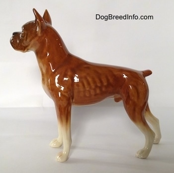 The left side of a brown with black and white Boxer dog figurine. The figurine has a short tail.