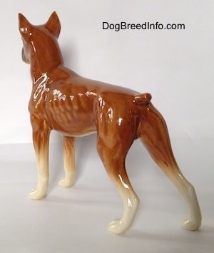 The back left side of a brown Boxer dog figurine. The figurine has detailed paws.