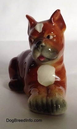A brown with white and black Boxer puppy figurine. The pink tongue of the figurine is sticking out.