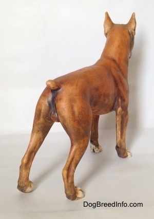 The back right side of a brown with black and white Boxer figurine with a matte finish. The tail of the figurine is short.