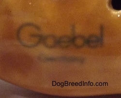 Close up - The underside of a brown with black mini Boxer dog porcelain figurine. On the underside is the Goerbel W.Germany logo.