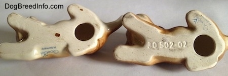 The underside of two brown with white Boxer puppy figurines. On the underside of the figurines is a hole with tha Goebel trademark 5 (TMK 5) logo, on the underside.