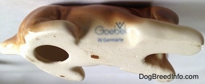 The underside of a Boxer puppy figurine. On the bottom is a hole and near its side is the Goebel W. Germany logo.