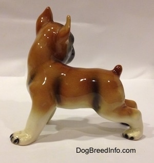 The left side of a brown with white and black porcelain Boxer dog figurine. The figurine has an arched up short tail.