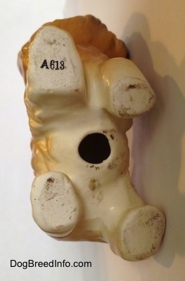 The underside of a Cairn Terrier figurine. On the underside is a hole in the middle and there is a letter/number comination - A613 - on the top right paw.