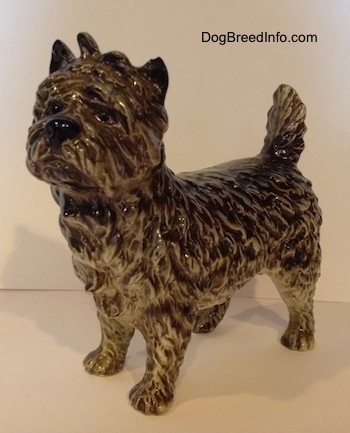 The front left side of a black and white Cairn Terrier figurine. The eyes of the figurine are black circles.