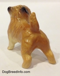 The back left side of a brown with black Cairn Terrier figurine. The figurine has a tail that is in the air.