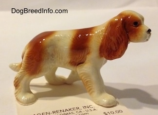 The right side of a red and white Cavalier King Charles Spaniel figurine. The figurine has fine hair details.