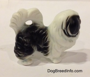 THe right side of a white and black bone china Japanese Chin dog figurine. The figurine has short limbs and a short body.