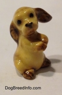 The right side of a tan with brown ceramic Cocker Spaniel puppy figurine. It has black circles for eyes.