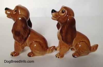 The left side of two brown and tan Cocker Spaniel puppy figurines. The figurines have short tails.