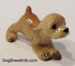 The front right side of a tan ceramic Cocker Spaniel puppy running figurine. It has fine eye details.