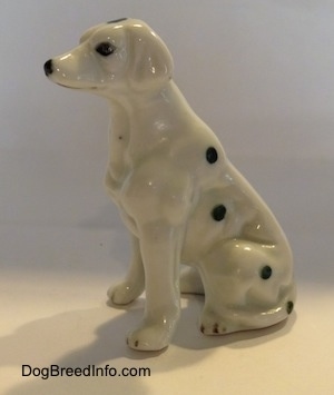 The left side of a Dalmatian puppy in a sitting pose figurine. Its ears are hard to differentiate from its body.