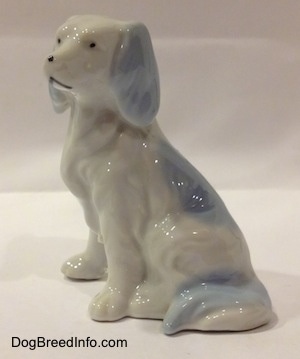 The left side of a bone china white with blue English Setter figurine. The tail of the figurine is attached to its legs.