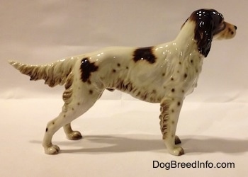 The right side of a porcelain figurine that is a brown and white English Setter. The trim of the figurine has brown hair details along the body and legs.