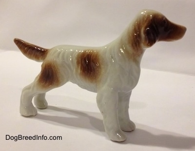 The right side of a bone china white and brown bone china English Setter figurine. The figurine has large brown spots on its body and it has fine hair details.