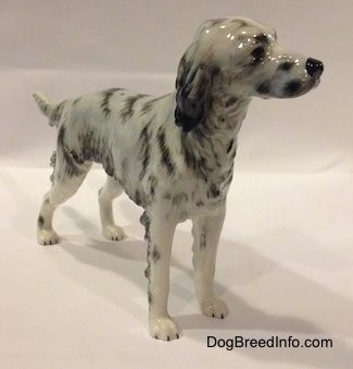 The front right side of porcelain figurine of a white and black English Setter. The figurine has black circles for eyes.