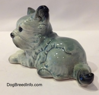 The back left side of a figurine of a white with black French Bull Tzu in a laying down pose figurine. The figurine has a black tipped tail.