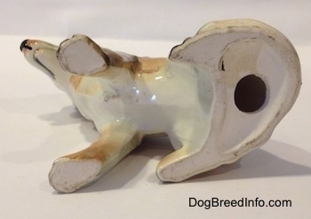 The bottom of a ceramic German Shepherd figurine. The figurine has a hole in the bottom.