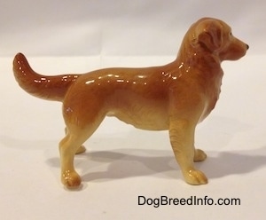 The right side of a brown with tan Golden Retriever figurine. The figurine has a tail that is level with its body, but the end of the tail is arched up.