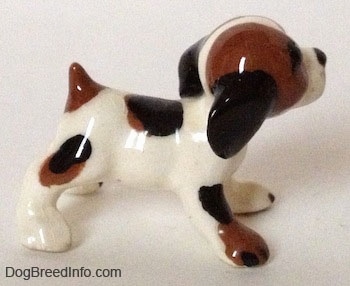 The right side of a vintage white with brown and black Hound dog figurine. The figurine has a medium sized body and it has a short tail.
