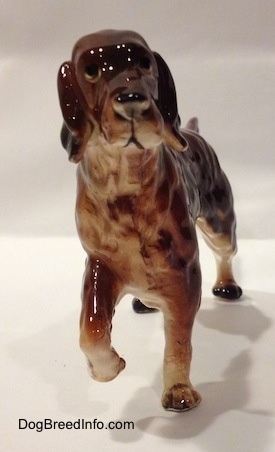 A ceramic brown with tan Irish Setter figurine pointing. The figurine has black circles for eyes.