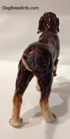 The back right side of a ceramic Irish Setter figurine. The tail of the figurine is up and level with its body.