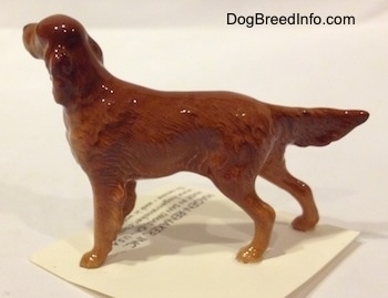 The left sdie of a brown Irish Setter figurine that has long legs and small paws.
