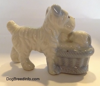 The back of a bone china Miniature Schnauzer with a basket of puppies next to her. The figurines have fine hair details.
